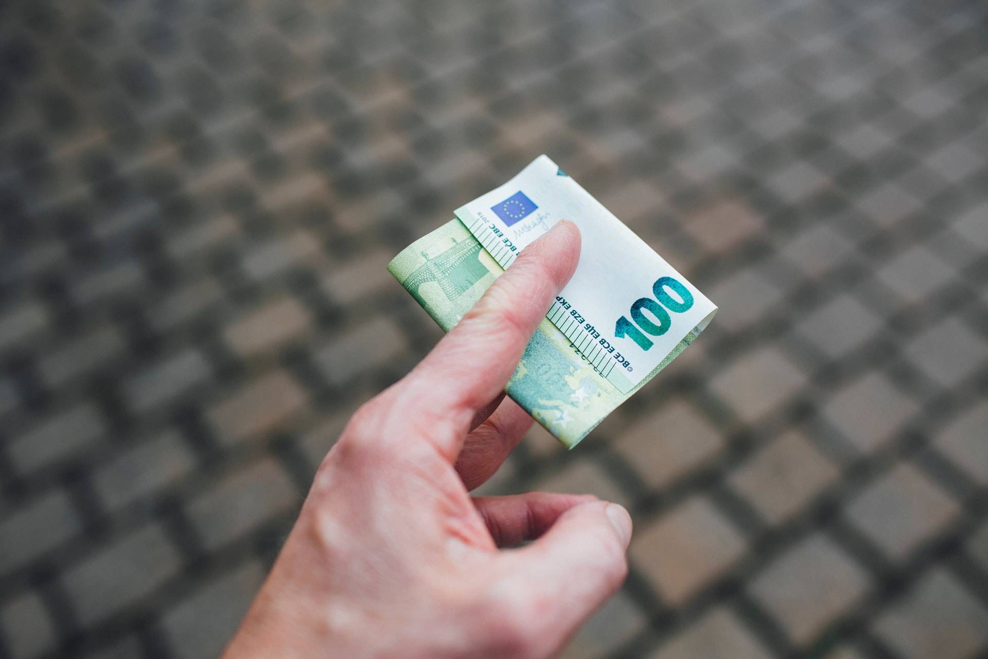 Personne qui tend un billet de 100€